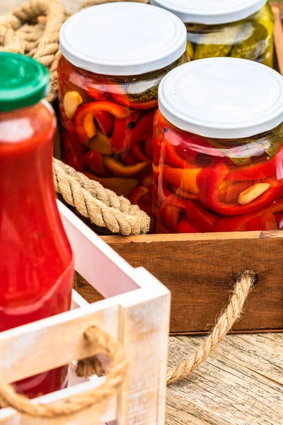 酢漬けの赤ピーマンとトマトソースのボトルとガラス瓶は素朴な組成物に隔離されています 酢漬け野菜の様々な保存食の概念 — ストック写真