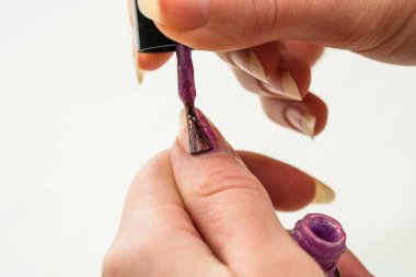 Manikür yapan kadın eller, beyaz arka planda altın rengi tırnak cilası. Deri ve tırnak bakımı konsepti