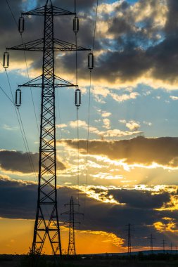 Güzel dramatik gökyüzü ve bulutlar, gün batımının ışıkları iletim kulesinin üzerinde (elektrik direği) bir tarlada.