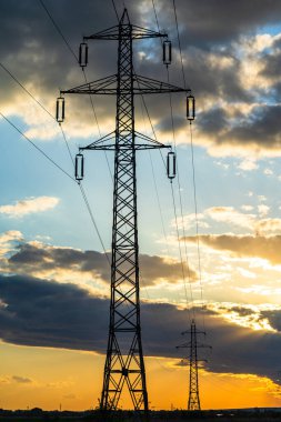 Güzel dramatik gökyüzü ve bulutlar, gün batımının ışıkları iletim kulesinin üzerinde (elektrik direği) bir tarlada.