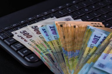 Lei banknotes on keyboard. Selective focus on stack of LEI romanian money. clipart