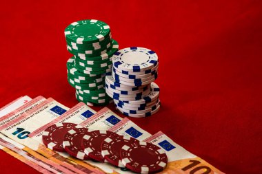 Kırmızı arkaplanda parası olan poker çipleri yığını, EURO para birimi