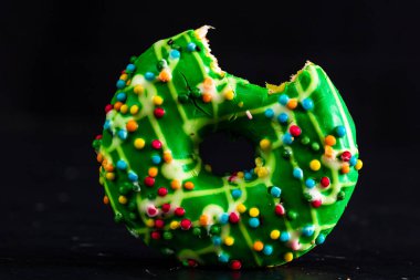 Yeşil jöleli donut ve serpiştirilmiş. Isırılmış renkli çörekleri kapat..
