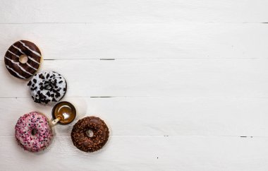 Beyaz ahşap masada renkli çörekler. Şekerli, şekerli, şekerli, şekerli, şekerli. Kopyalama alanı olan üst görünüm