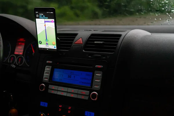 車のダッシュボード上のスマートフォン上の波の地図アプリを使用して ドライバは 雨の夜に日没時に街のトラフィックを介して正しいルートを示すために地図アプリを使用しています ブカレスト ルーマニア 2020年 — ストック写真