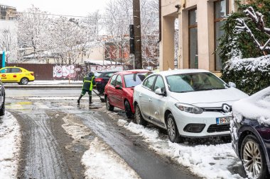 Romanya 'nın Bükreş kentindeki karlı yolu temizleyen kar temizleme ve işçi 2021