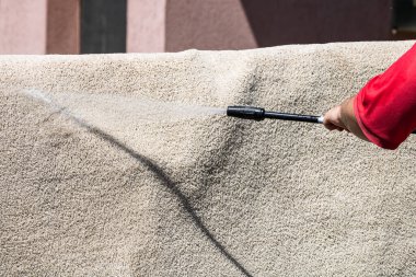 Yüksek basınçlı çamaşır makinesiyle halıları yıkayın. Yüksek basınçlı suyu yıkamak için halıyı silahla temizlemek. Ev temizliği kavramı.