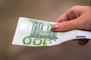 Kız elleri para veriyor. Bulanık bir arkaplanda EURO banknotları tutuluyor