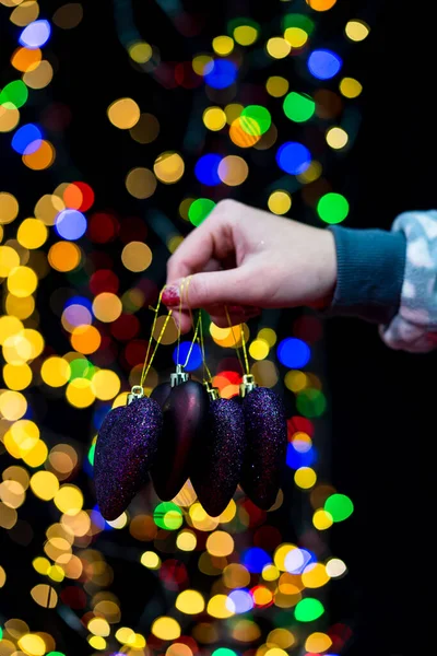 Woman's hands hold christmas decoration. Christmas and New Year holidays background, winter season with Christmas ornaments and blurred lights