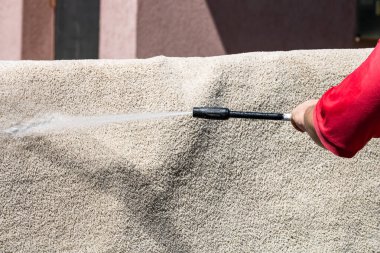 Yüksek basınçlı çamaşır makinesiyle halıları yıkayın. Yüksek basınçlı suyu yıkamak için halıyı silahla temizlemek. Ev temizliği kavramı.