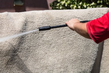 Yüksek basınçlı çamaşır makinesiyle halıları yıkayın. Yüksek basınçlı suyu yıkamak için halıyı silahla temizlemek. Ev temizliği kavramı.