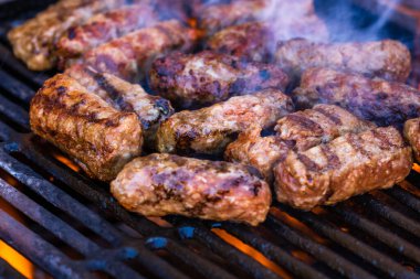 Mangalda mici ya da mititei denilen rulo köfteleri hazırlıyorum. Izgarayı alev ve dumanla yakın..