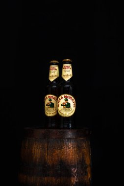 Bir şişe Birra Moretti birası. Ahşap fıçının üzerinde, koyu arkaplanlı. Bükreş, Romanya, 2021