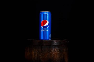 Koyu arkaplanlı, tahta fıçının üzerinde bir kutu Pepsi Cola. Bükreş, Romanya, 2021