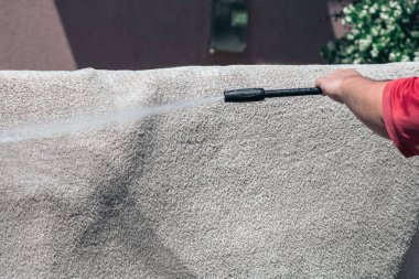 Yüksek basınçlı çamaşır makinesiyle halıları yıkayın. Yüksek basınçlı suyu yıkamak için halıyı silahla temizlemek. Ev temizliği kavramı.