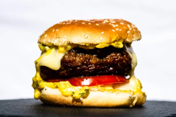Lezzetli sığır etli çizburgerin ayrıntıları beyaz arka planda izole edilmiş. Turşulu çizburger, domates, soğan, erimiş peynir..