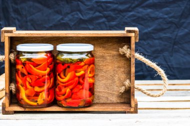Cam kavanozlu tahta sandık, turşulu kırmızı çan biberi. Konserve gıda konsepti, yalıtılmış konserve sebzeler..