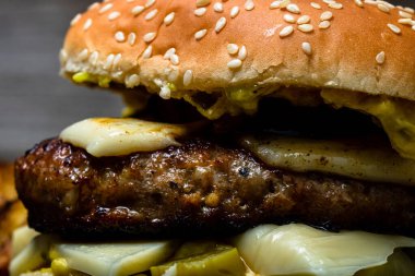 Tahta bir masada taze peynirli burger ve kızarmış patates manzarası.