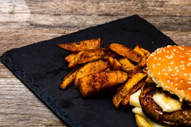 Ev yapımı taze peynirli burger ve ahşap masada kızarmış patates.