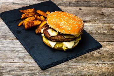 Ev yapımı taze peynirli burger ve ahşap masada kızarmış patates.