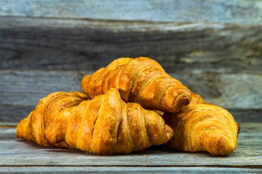 Tahtaya izole edilmiş lezzetli, taze kruvasanlar. Fransız kahvaltı konsepti.