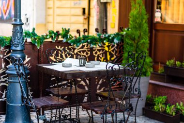 Romanya 'nın Bükreş kentindeki bir açık hava restoranında boş sandalyeli boş masaları kapat, 2021