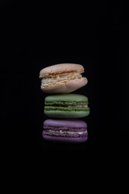 Siyah arka planda izole edilmiş rengarenk badem kurabiyeleri, Fransız badem kurabiyeleri.