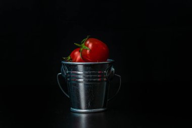 Mini dekoratif kova ve domateslerle kompozisyona odaklan. Kiraz domatesli küçük metal kova.