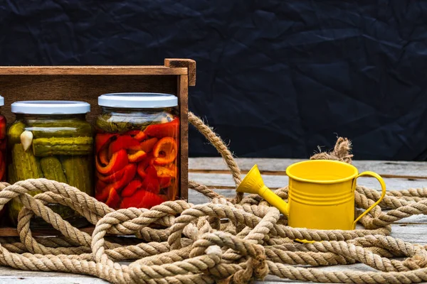 赤ピーマンを漬けガラス瓶と木製のクレートとキュウリ 孤立した 酢漬け野菜の様々な瓶 素朴な構成で保存食の概念 — ストック写真