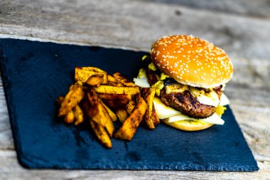 Ev yapımı taze peynirli burger ve ahşap masada kızarmış patates.