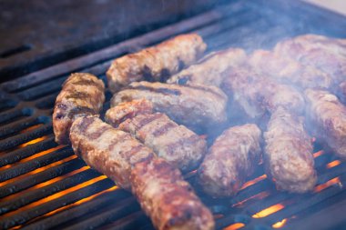 Mangalda mici ya da mititei denilen rulo köfteleri hazırlıyorum. Izgarayı alev ve dumanla yakın..