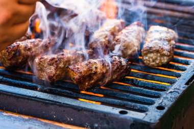 Mangalda mici ya da mititei denilen rulo köfteleri hazırlıyorum. Izgarayı alev ve dumanla yakın..
