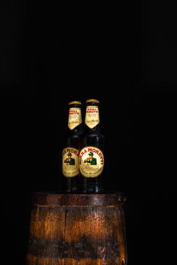 Bir şişe Birra Moretti birası. Ahşap fıçının üzerinde, koyu arkaplanlı. Bükreş, Romanya, 2021