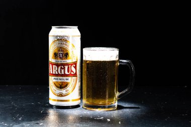 Bir kutu Argus birası ve arka planda bira bardağı. Romanya 'nın Bükreş kentinde 2021 yılında çekilen illüstrasyon fotoğrafı