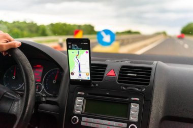 Romanya 'nın Bükreş kentindeki Waze Haritaları uygulamasını kullanan sürücü, akıllı telefondan araba gösterge paneline waze haritası uygulaması kullanıyor ve kullanıyor