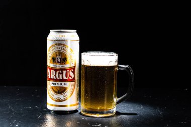 Bir kutu Argus birası ve arka planda bira bardağı. Romanya 'nın Bükreş kentinde 2021 yılında çekilen illüstrasyon fotoğrafı