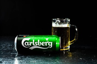 Arka planda bir kutu Carlsberg birası ve bira bardağı. Romanya 'nın Bükreş kentinde 2021 yılında çekilen illüstrasyon fotoğrafı