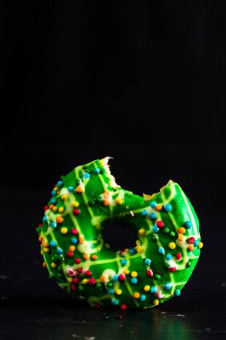 Yeşil jöleli donut ve serpiştirilmiş. Isırılmış renkli çörekleri kapat..