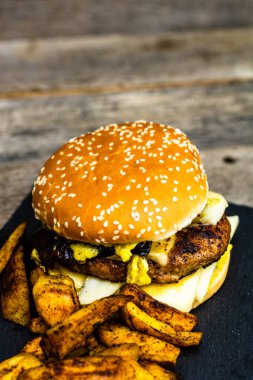 Ev yapımı taze peynirli burger ve ahşap masada kızarmış patates.