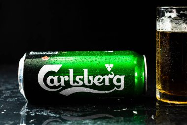 Arka planda bir kutu Carlsberg birası ve bira bardağı. Romanya 'nın Bükreş kentinde 2021 yılında çekilen illüstrasyon fotoğrafı