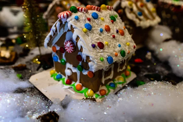 Renkli zencefilli kurabiye evi, bulanık arka planda, Noel süslemesiyle izole edilmiş..