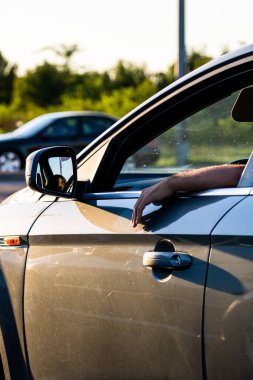 Sürücü, açık pencereli, arabanın kapısında el ele tutuşup trafik konseptini bekliyor. Bükreş, Romanya, 2021