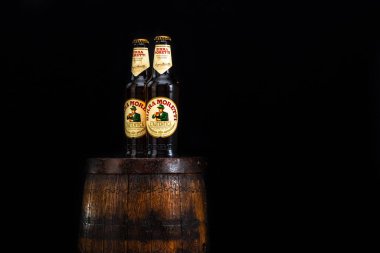 Bir şişe Birra Moretti birası. Ahşap fıçının üzerinde, koyu arkaplanlı. Bükreş, Romanya, 2021