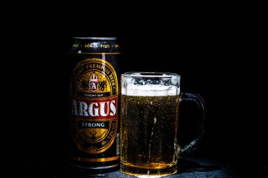 Bir kutu Argus birası ve arka planda bira bardağı. Romanya 'nın Bükreş kentinde 2021 yılında çekilen illüstrasyon fotoğrafı