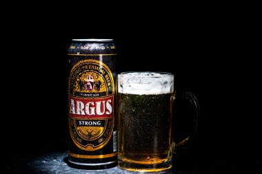 Bir kutu Argus birası ve arka planda bira bardağı. Romanya 'nın Bükreş kentinde 2021 yılında çekilen illüstrasyon fotoğrafı