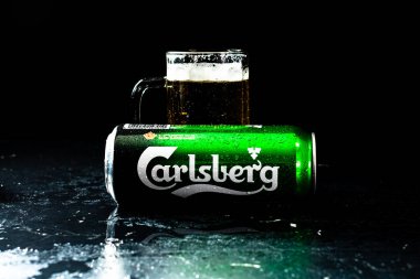 Arka planda bir kutu Carlsberg birası ve bira bardağı. Romanya 'nın Bükreş kentinde 2021 yılında çekilen illüstrasyon fotoğrafı