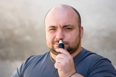 Erkek tıraş makinesi ya da jilet kullanarak burun kıllarını kesiyor.