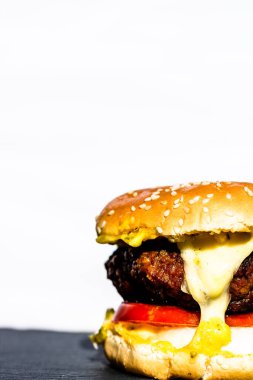 Beyaz arka planda erimiş peynirli taze sığır etli çizburger.