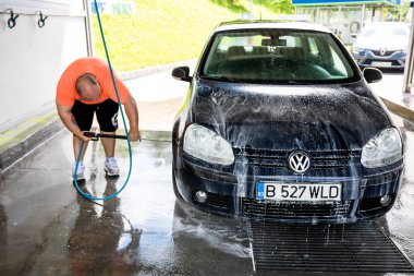 Otomobil yıkama istasyonunda araba yıkama ve temizleme. Romanya 'nın Bükreş kentinde yüksek basınçlı su kullanan araba yıkama, 2021