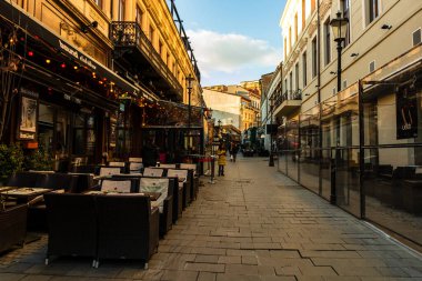 Romanya 'nın Bükreş kentindeki bir açık hava restoranında boş sandalyeli boş masaları kapat, 2021